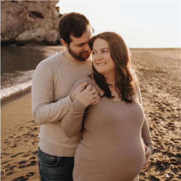 Een zwangere Jenna en haar patner op het strand in Spanje