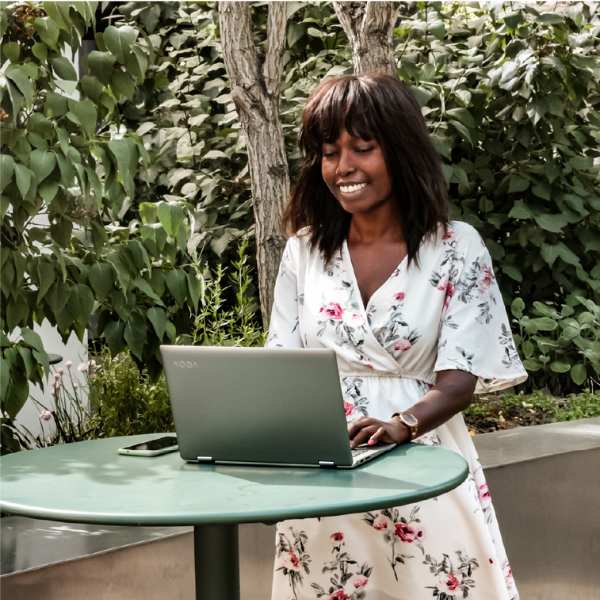 Ina De Becker buiten aan het werk, staand bij haar laptop