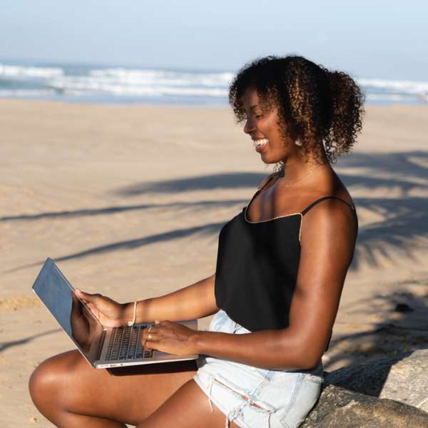 Brendy, als carrière coach, met haar laptop aan het strand